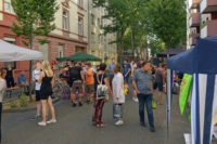 Totale über die Straße, am Rand Schirme und Pavillons der Stände, in der Mitte Besucher, das Fest ist gut gefüllt