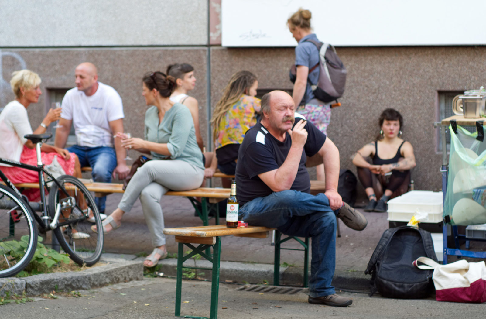 Zwischen anderen Besuchern sitzt Joachim Durang auf einer Bank und beobachtet vor seinem Auftritt das Fest