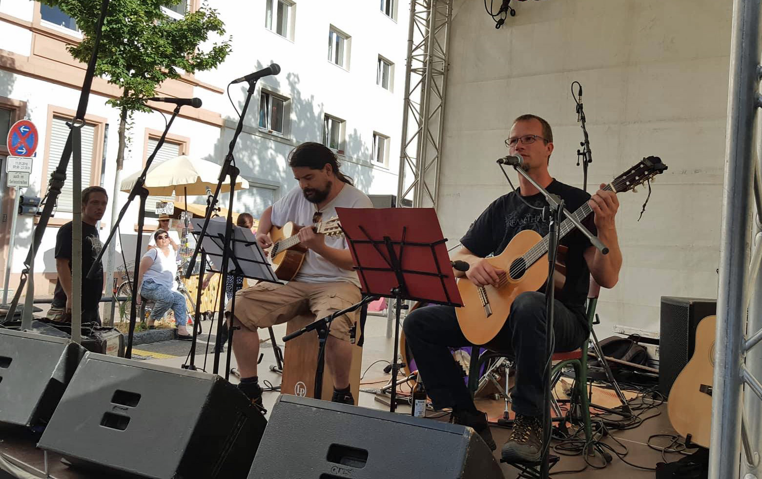 Speerträge und Royce auf der Bühne, von schräg seitwärts. Beide spielen Gitarre, Speerträger singt, neben der Bühne interessierte Zuhörer