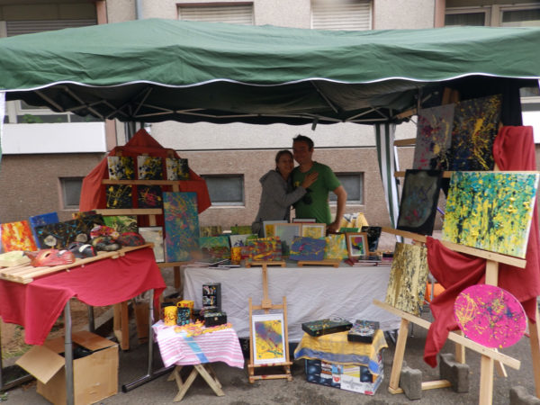 Kunststand von Frau Fenster, eine bunte Menge von Nutzgegenständen und BIldern in der ihr eigenen abstrakten Gestaltung und Farbgebung