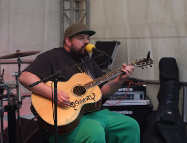 Singer-Songwriter (im weitesten Sinne) Yohazid auf der Bühne, sitzend, mit einer akustischen Gitarre